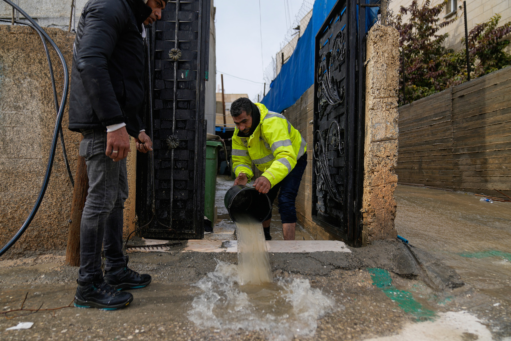 A man uses a bucket to drain his flooded house during a powerful winter system that caused the death of two Palestinians, in the West Bank town of Anata, southeast of Ramallah, Tuesday, Jan. 13, 2026. (AP Photo/Nasser Nasser)