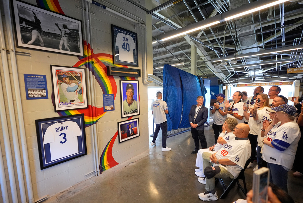 Attendees reacts during a ceremony prior to a baseball game to unveil a tribute to LGBTQ+ trailblazers and former Los Angeles Dodgers players Billy Bean and Glenn Burke, who were among the first professional athletes to identify as gay, Friday, June 5, 2026, in Los Angeles. (AP Photo/Mark J. Terrill)