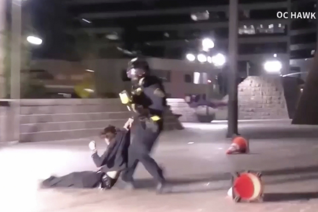 In this image taken from a video provided by OC Hawk, a federal officer drags a demonstrator hit in the face with a projectile fired from close range by an officer during a protest in Santa Ana, Calif., Friday, Jan. 9, 2026. (OC Hawk via AP)