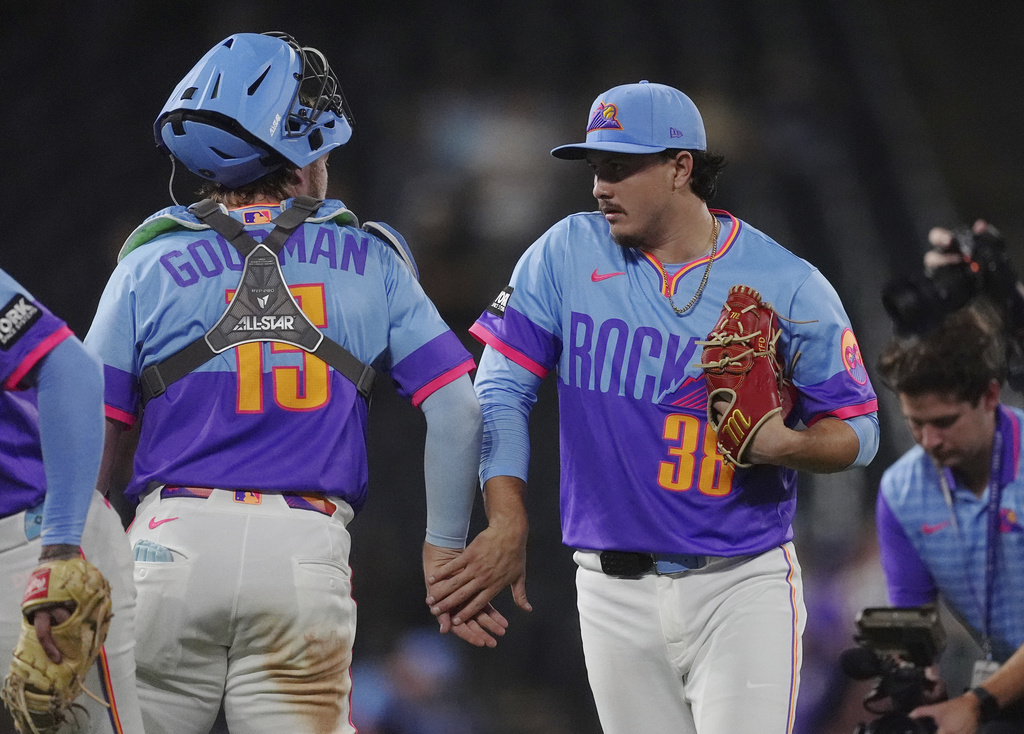 Colorado Rockies catcher Hunter Goodman, left, congratulates relief pitcher Victor Vodnik after defeating the Arizona Diamondbacks in a baseball game Friday, Aug. 15, 2025, in Denver. (AP Photo/David Zalubowski)