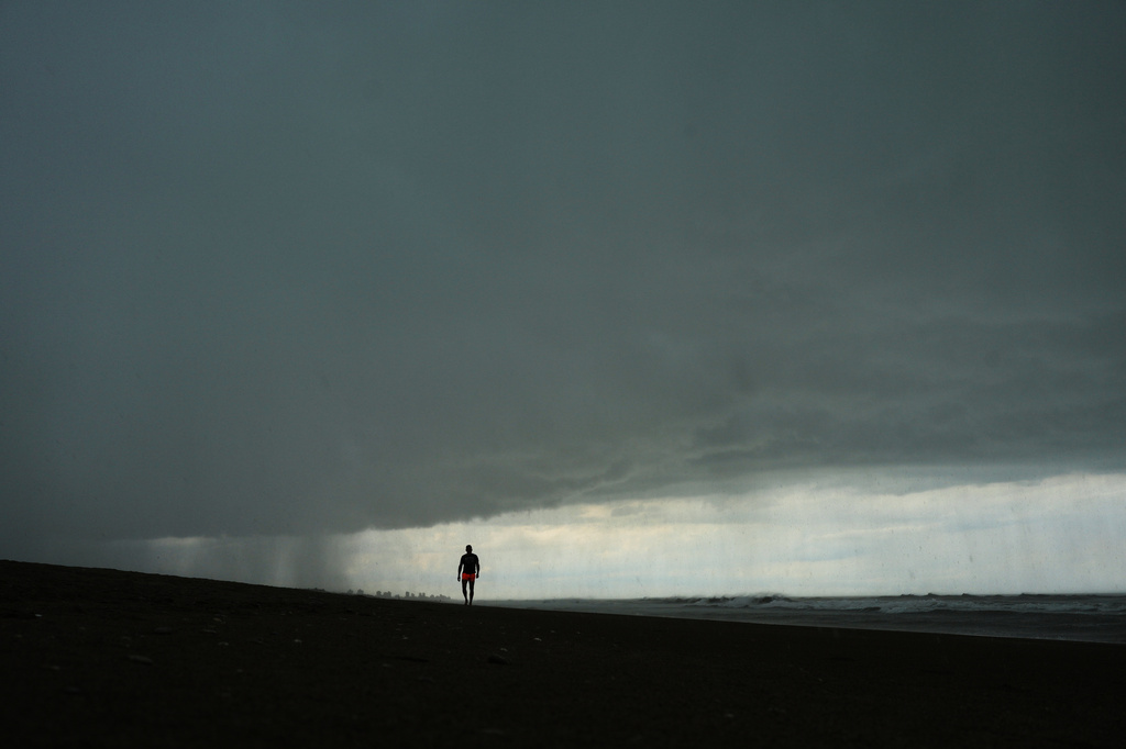 A man walks on the beach as a rain storm moves in to Mar de las Pampas, Argentina, Friday, April 3, 2026. (AP Photo/Rodrigo Abd)