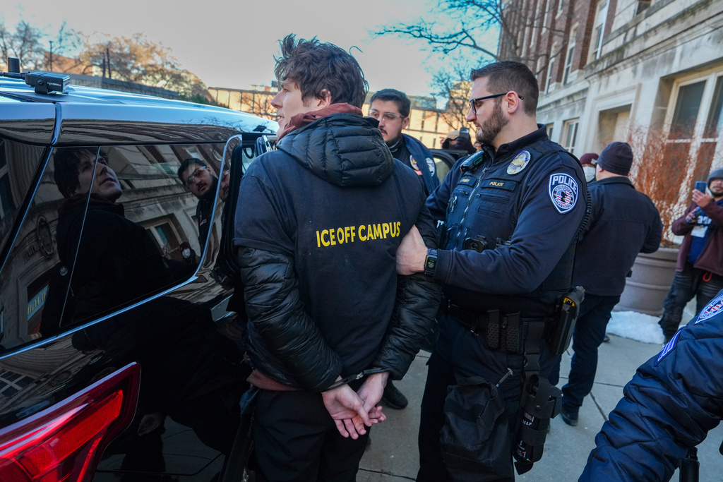 A student protester is detained by University of Minnesota Police for chaining himself to a door on campus during an anti-ICE protest, on Friday, Feb. 6, 2026, in Minneapolis. (AP Photo/Ryan Murphy)