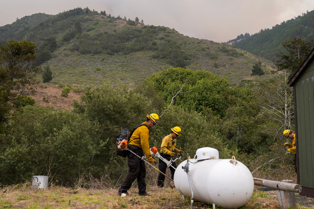 Crews trim bushes around the U.S. Forest Service fire station to help protect structures from the Plaskett Fire near Big Sur, Calif., Thursday, Aug. 27, 2026. (AP Photo/Nic Coury)