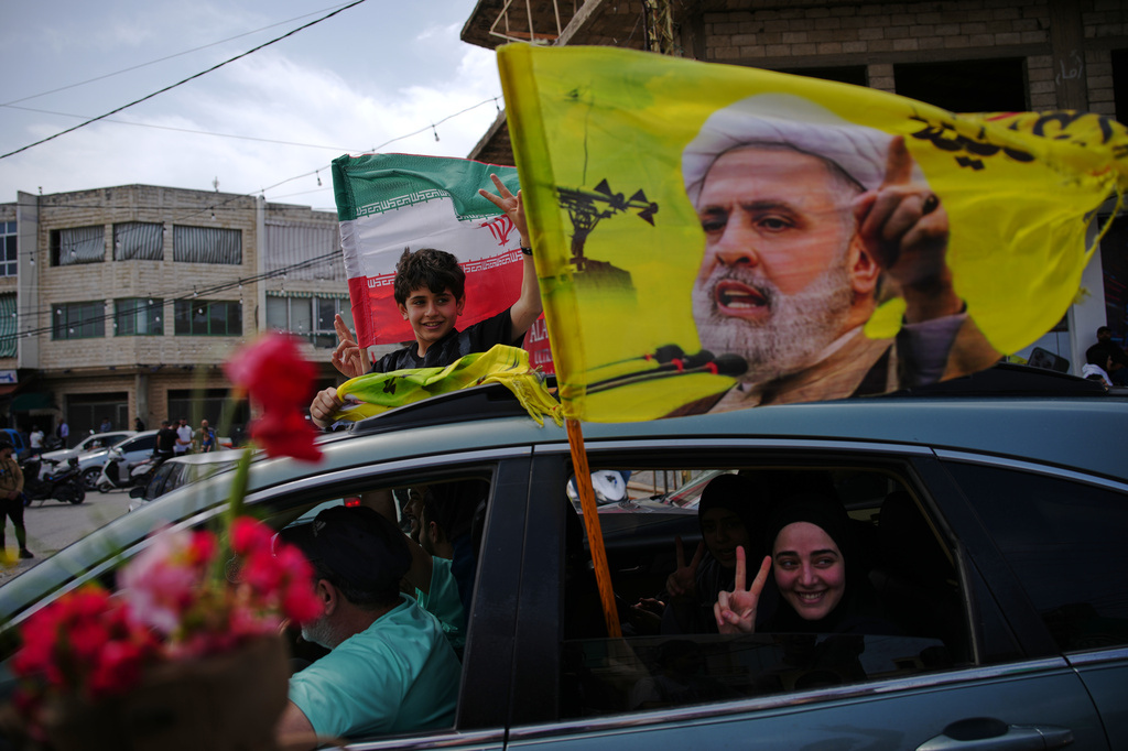 Displaced residents wave a flag with the image of Hezbollah leader Naim Qassem as they return to their villages following a ceasefire between Israel and Hezbollah, in Zefta, southern Lebanon, Friday, April 17, 2026. (AP Photo/Hassan Ammar)