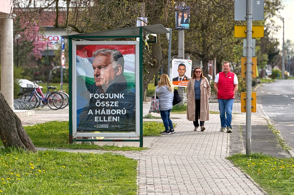 People walk by an electoral poster showing Hungarian Prime Minister Viktor Orban and the slogan "Let's stand together against the war!" in Albertirsa, Hungary, Thursday, April 9, 2026. (AP Photo/Eldar Emric)