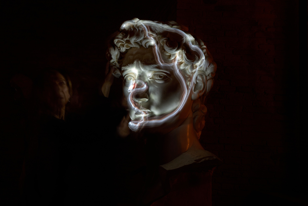 Stefania Terre, who is blind, uses a small light on her fingers while touching a life-size reproduction of the head of Michelangelo's David as she poses for a long-exposure photograph at the Omero Tactile Museum in Ancona, Italy, Thursday, Jan. 15, 2026. (AP Photo/Alessandra Tarantino)