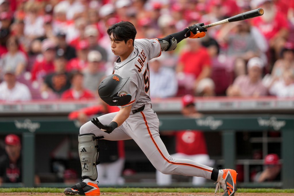 San Francisco Giants' Jung Hoo Lee catches his batting helmet after it came off while swinging at a strike during the second inning of a baseball game against the Cincinnati Reds in Cincinnati, Thursday, April 16, 2026. (AP Photo/Carolyn Kaster)