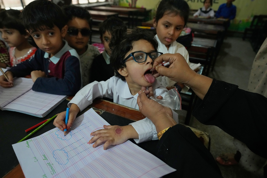 A health worker administers a polio vaccine to a child at a school in Lahore, Pakistan, Monday, April 13, 2026. (AP Photo/K.M. Chaudary)