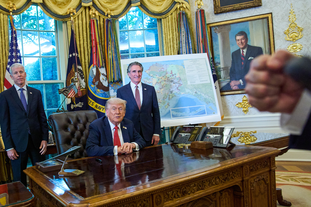 President Donald Trump congratulates a reporter on how young he looks, during an executive order signing in the Oval Office at the White House, Monday, Oct. 6, 2025, in Washington, as Energy Secretary Chris Wright, left, and Interior Secretary Doug Burgum listen. (AP Photo/Jacquelyn Martin)