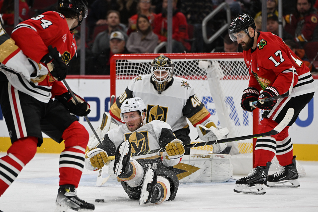 Vegas Golden Knights' Jeremy Lauzon (5) battles Chicago Blackhawks' Colton Dach (34) for the puck during the second period of an NHL hockey game Sunday, Jan. 4, 2026, in Chicago. (AP Photo/Paul Beaty)
