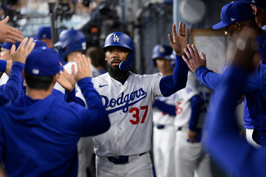 Los Angeles Dodgers' Teoscar Hernández is greeted after scoring on a sacrifice fly hit by Miguel Rojas during the fourth inning of a baseball game against the Colorado Rockies in Los Angeles, Monday, July 6, 2026. (AP Photo/Kyusung Gong)