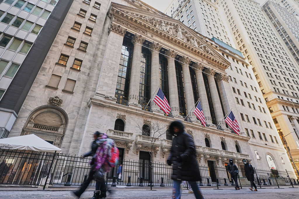 Morning commuters pass the New York Stock Exchange, Tuesday, Jan. 20, 2026. (AP Photo/Richard Drew)