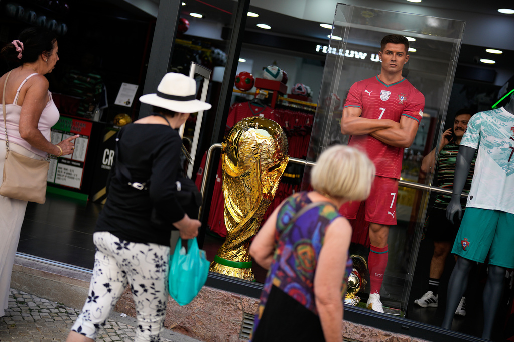 A enlarged replica of the FIFA World Cup trophy is displayed in a shop window next to a mannequin resembling Portugal soccer team captain Cristiano Ronaldo as tourists walk by in downtown Lisbon, Wednesday, May 20, 2026, ahead of the 2026 soccer World Cup. (AP Photo/Armando Franca)