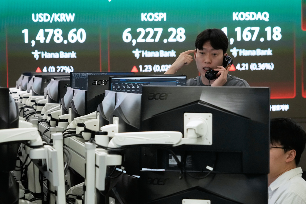 A currency trader talks on the phone near a screen showing the Korea Composite Stock Price Index (KOSPI), top center, and the foreign exchange rate between U.S. dollar and South Korean won, top center left, at the foreign exchange dealing room of the Hana Bank headquarters, in Seoul, South Korea, Friday, April 17, 2026. (AP Photo/Ahn Young-joon)