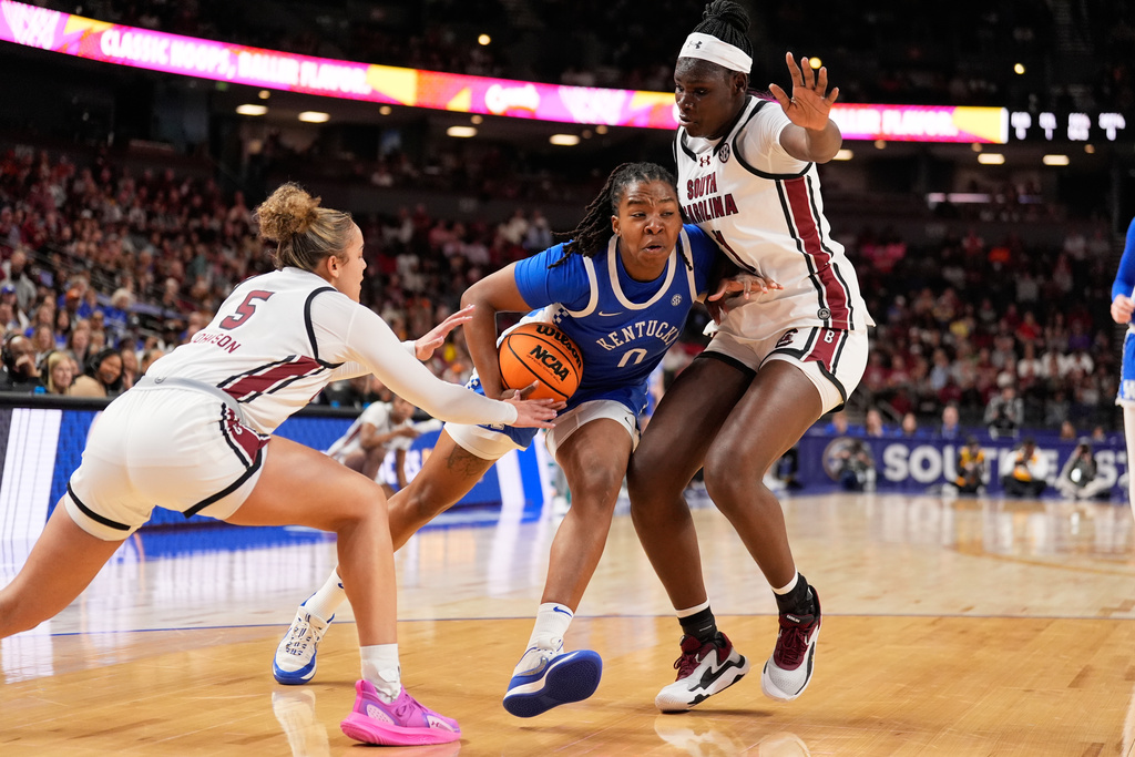 Kentucky guard Jordan Obi drives to the basket between South Carolina guard Tessa Johnson and center Madina Okot during first half of an NCAA college basketball game in the quarterfinals of the Southeastern Conference tournament, Friday, March 6, 2026, in Greenville, S.C. (AP Photo/Chris Carlson)