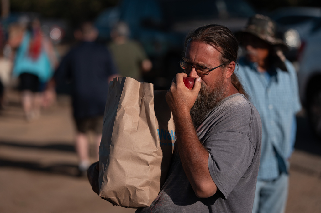 Matthew Cole smells a nectarine after receiving a bag of fruit during a free giveaway at Cesar Mora's orchard in Reedley, Calif., Wednesday, July 1, 2026. (AP Photo/Jae C. Hong)