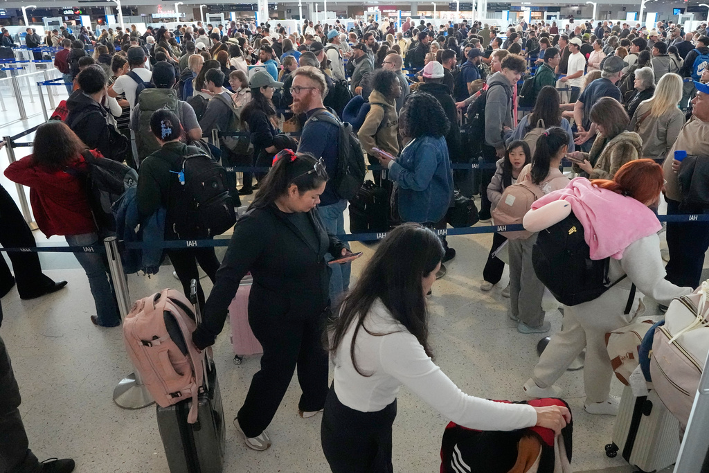 Passengers wait in a long security checkpoint line at George Bush Intercontinental Airport Thursday, March 19, 2026, in Houston. (AP Photo/David J. Phillip)