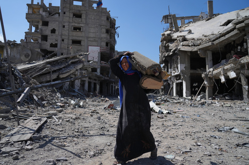 An elderly displaced Palestinian woman carries an item past destroyed buildings in Khan Younis, southern Gaza Strip, Friday, Oct. 10, 2025, after Israel and Hamas agreed to a pause in their war and the release of the remaining hostages. (AP Photo/Jehad Alshrafi) An elderly displaced Palestinian woman carries an item past destroyed buildings in Khan Younis, southern Gaza Strip, Friday, Oct. 10, 2025, after Israel and Hamas agreed to a pause in their war and the release of the remaining hostages. (AP Photo/Jehad Alshrafi)