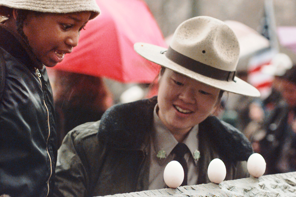 FILE - Malik Shabazz Pizzaro, left, with the helpf froom urban park ranger June Yoo of the New York City Department of Parks and Recreationm reacts after balancing an egg on a Central Park wall as part of a vernal equinox celebration in New York, Thursday, March 20, 1997. (AP Photo/Mark Lennihan, File)