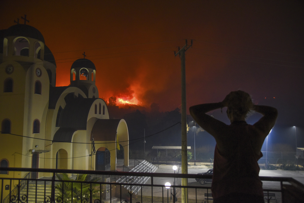 A resident reacts as blazes burn a hill during a wildfire in the village of Tsoukalaiika near Patras city, western Greece, Tuesday, Aug. 12, 2025. (AP Photo/Andreas Alexopoulos)