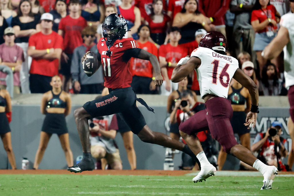 North Carolina State quarterback CJ Bailey (11) runs the ball away from Virginia Tech linebacker Noah Chambers (16) during the first half of an NCAA college football game in Raleigh, N.C., Saturday, Sept. 27, 2025. (AP Photo/Karl DeBlaker)