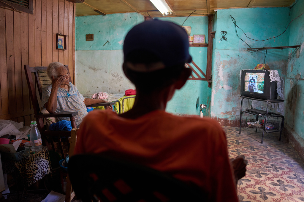 Julia Barcelo, 83, who is recovering from breast cancer treatment, and a visiting relative watch television at her home in Old Havana, Cuba, Friday, April 10, 2026. (AP Photo/Ramon Espinosa)