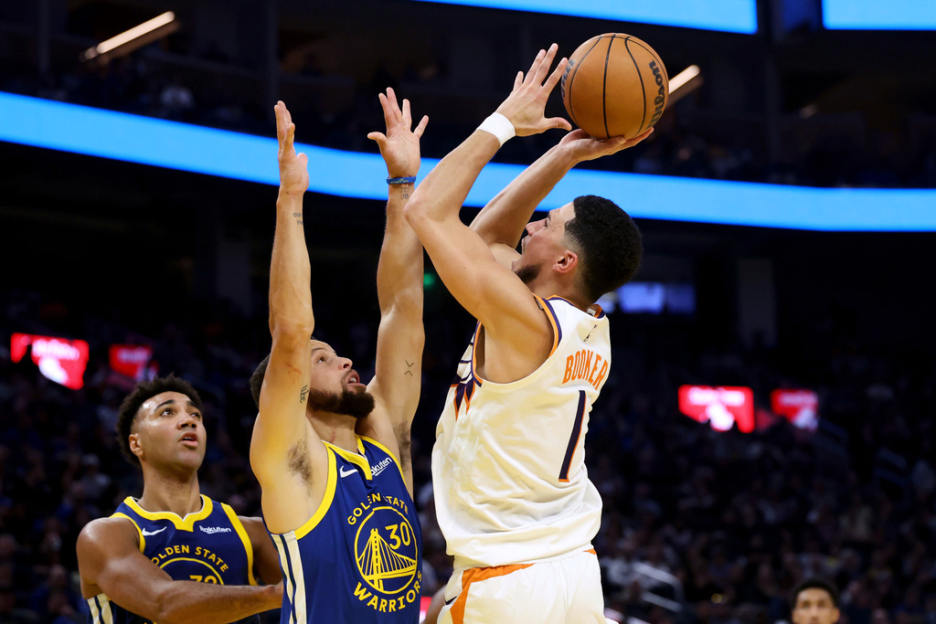 Phoenix Suns guard Devin Booker (1) shoots against Golden State Warriors guard Stephen Curry (30) during the first half of an NBA basketball game in San Francisco, Tuesday, Nov. 4, 2025. (AP Photo/Jed Jacobsohn)