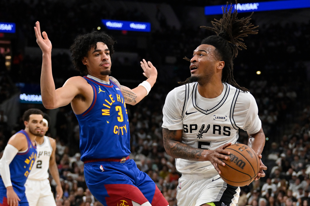 San Antonio Spurs guard Stephon Castle (5) drives against Denver Nuggets guard Julian Strawther during the first half of an NBA basketball game, Sunday, April 12, 2026, in San Antonio. (AP Photo/Darren Abate)