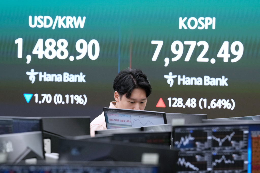 A currency trader watches monitors near a screen showing the Korea Composite Stock Price Index (KOSPI), right, and the foreign exchange rate between U.S. dollar and South Korean won at the foreign exchange dealing room of the Hana Bank headquarters in Seoul, South Korea, Thursday, May 14, 2026. (AP Photo/Ahn Young-joon)