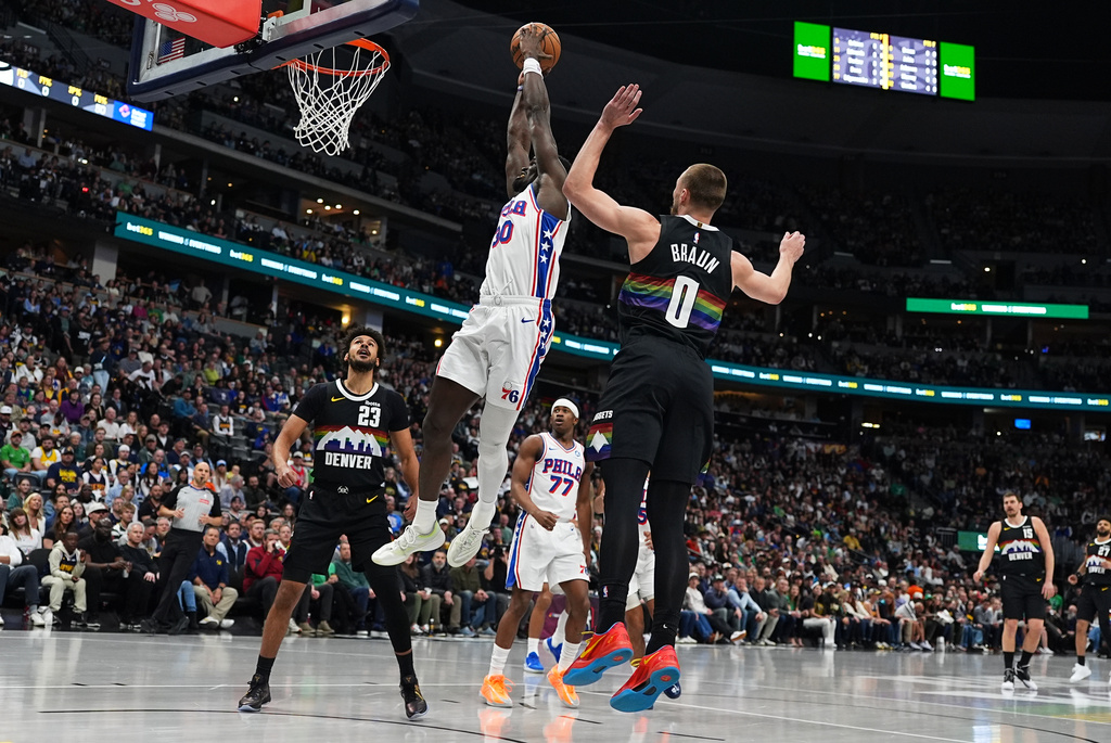 Philadelphia 76ers forward Adem Bona drives between Denver Nuggets forward Cameron Johnson, back, and guard Christian Braun, front, to dunk the ball for a basket in the first half of an NBA basketball game Tuesday, March 17, 2026, in Denver. (AP Photo/David Zalubowski)