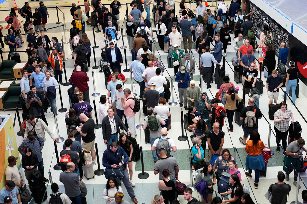 Travelers wait in long security checkpoint lines at George Bush Intercontinental Airport Friday, March 27, 2026, in Houston. (AP Photo/David J. Phillip)