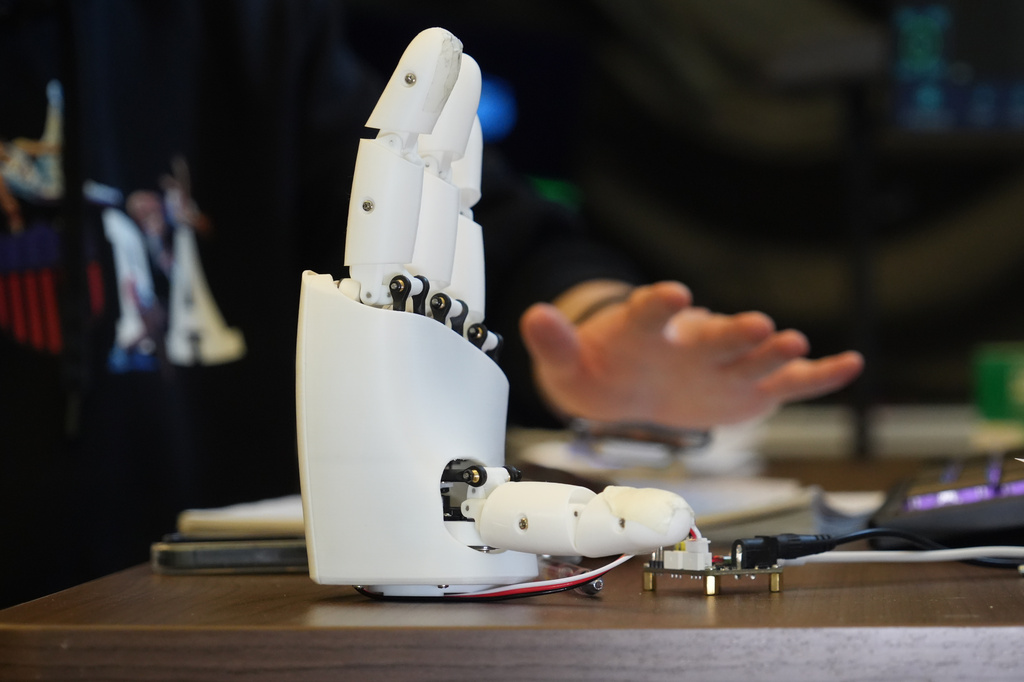 Massachusetts Institute of Technology mechanical engineering graduate student Dian Li demonstrates how an ultrasound wristband can help a robotic hand mimic full hand motions in Cambridge, Mass, on Tuesday, April 14, 2026. (AP Photo/Rodrique Ngowi)