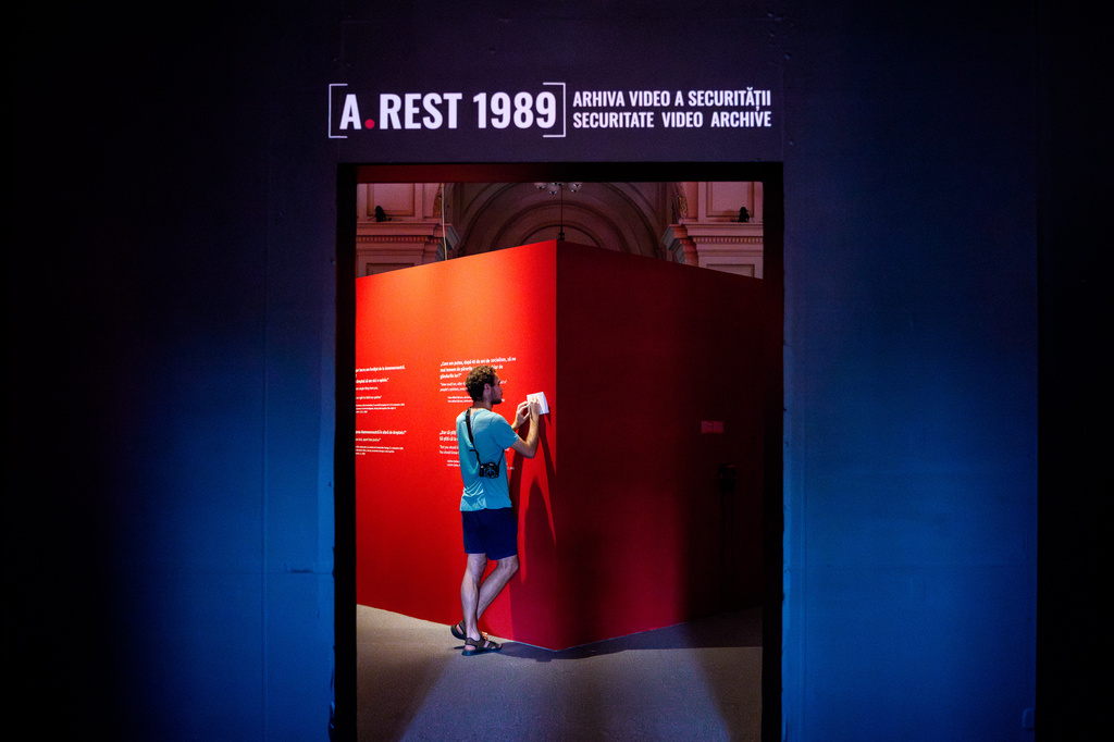 A man copies transcripts from Communist era surveillance tapes during the opening of the "A.REST 1989 — The Securitate Video Archive" exhibition, at the National History Museum of Romania, in Bucharest, Romania, Tuesday, June 16, 2026. (AP Photo/Andreea Alexandru)