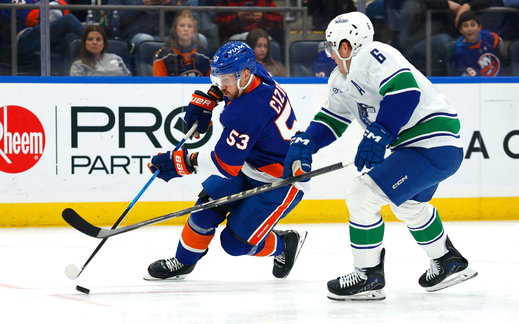 New York Islanders center Casey Cizikas (53) plays the puck against Vancouver Canucks right wing Brock Boeser (6) during the second period of an NHL hockey game, Friday, Dec. 19, 2025, in Elmont, NY. (AP Photo/Noah K. Murray)