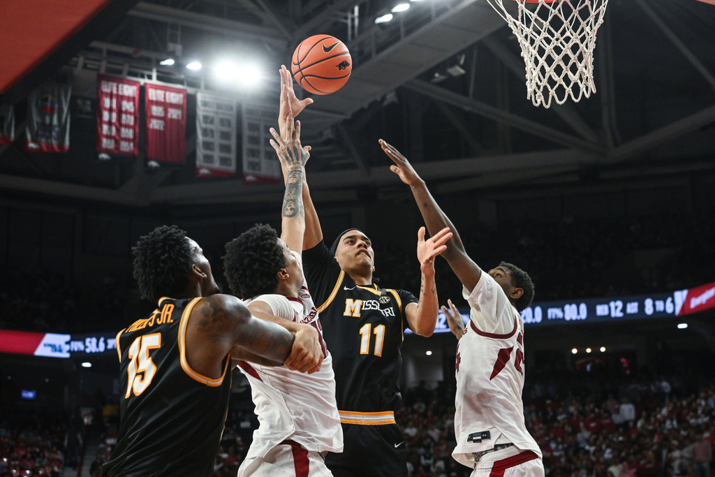 Missouri guard Trent Pierce (11) tries to drive past Arkansas defenders Malique Ewin, second from left, and Billy Richmond III, right, during an NCAA college basketball game Saturday, Feb. 21, 2026, in Fayetteville, Ark. (AP Photo/Michael Woods)