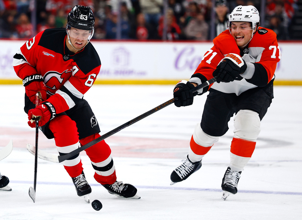New Jersey Devils left wing Jesper Bratt (63) plays the puck against Philadelphia Flyers right wing Tyson Foerster (71) during the second period of an NHL hockey game, Saturday, Nov. 29, 2025, in Newark, N.J. (AP Photo/Noah K. Murray)