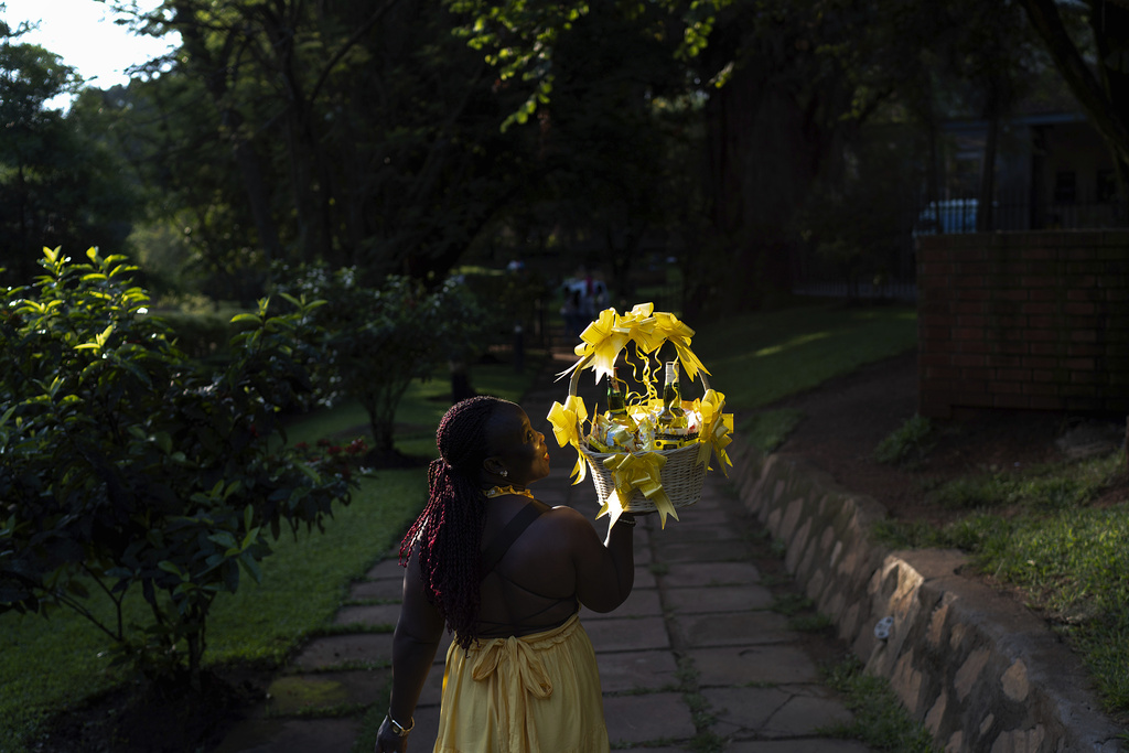 A woman carries a gift basket as she arrives at a park to attend a friend's birthday party, Sunday, Nov. 24, 2024, in Kampala, Uganda, where about three-fourths of Uganda's 43 million people are under 35, to according to UNICEF. (AP Photo/David Goldman)