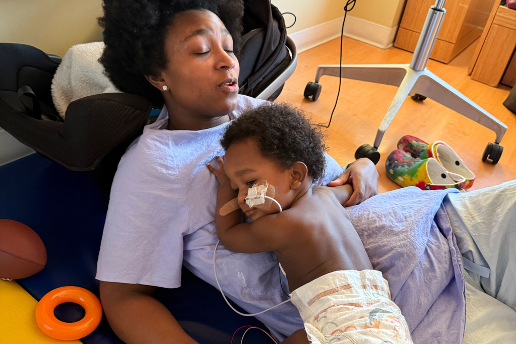 In this photo provided by the family, Ashaan Carter lies on his mother, Angel Carter, at a children's hospital in Portland, Ore., in November 2025, during his treatment for infant botulism after drinking ByHeart baby formula donated to vulnerable families, before a national recall of all of the products. (David Orphey via AP)