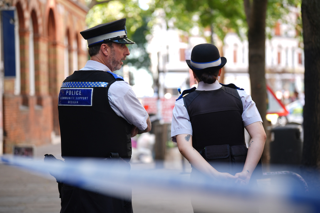 Police officers stand near the scene on Endell Street in Covent Garden, after four men were stabbed, in central London, Wednesday Aug. 5, 2026. PA Photo. (James Manning/PA via AP)