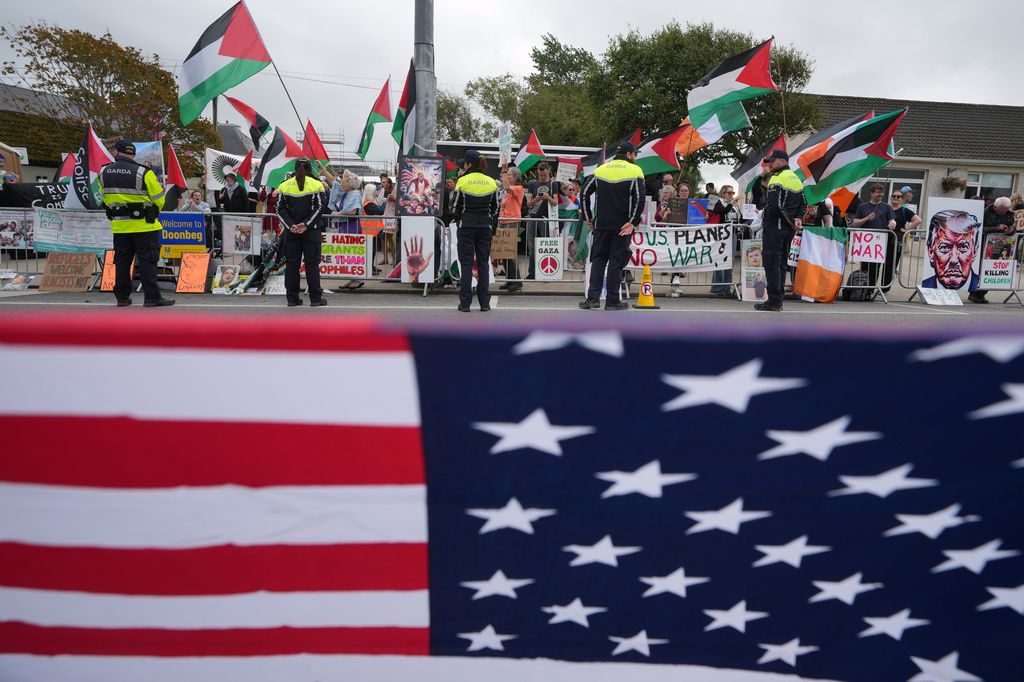 A flag of the United States of America is fixed on a fence opposite protesters during U.S. President Donald Trump's visit to the Irish Open at the Trump International Golf Links course in Doonbeg, Ireland, Sunday, Sept. 13, 2026.(AP Photo/Kin Cheung)