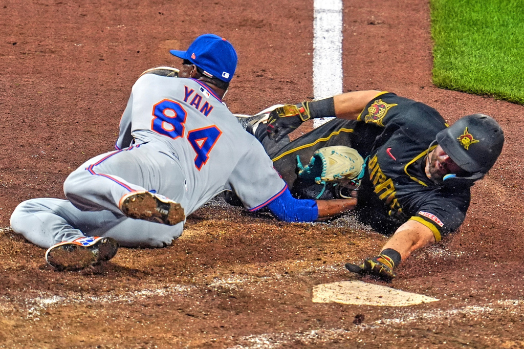 New York Mets pitcher Jefry Yan (84) tags out Pittsburgh Pirates' Jared Triolo who was attempting to score on a wild pitch during the seventh inning of a baseball game in Pittsburgh, Friday, Aug. 7, 2026. (AP Photo/Gene J. Puskar)