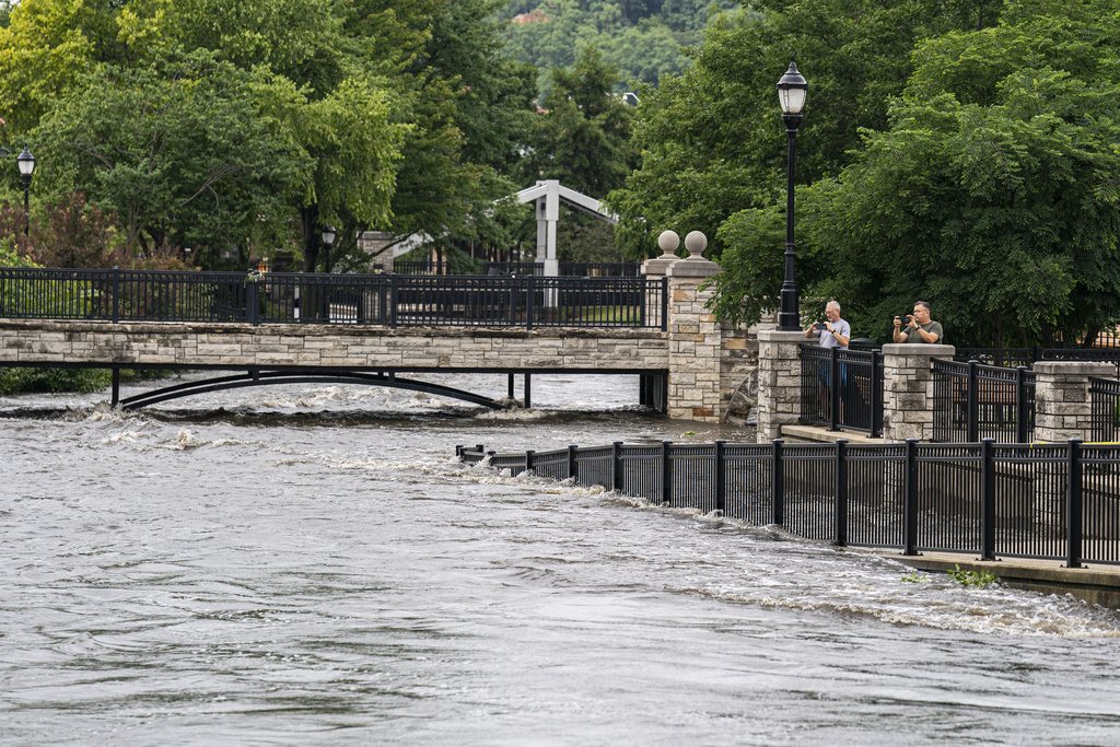 People watch along the Fox River Monday, Aug. 11, 2025, in Waukesha, Wis. (AP Photo/Andy Manis)