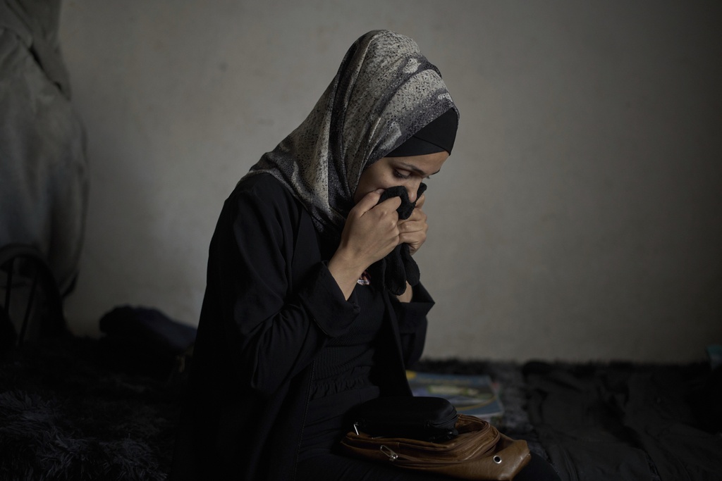 Anwar al-Heimouni, 29, smells the gloves of her 12-year-old son, Ayman al-Heimouni, who was killed by Israeli fire, in their home in the West Bank city of Hebron, March 26, 2025. (AP Photo/Leo Correa)