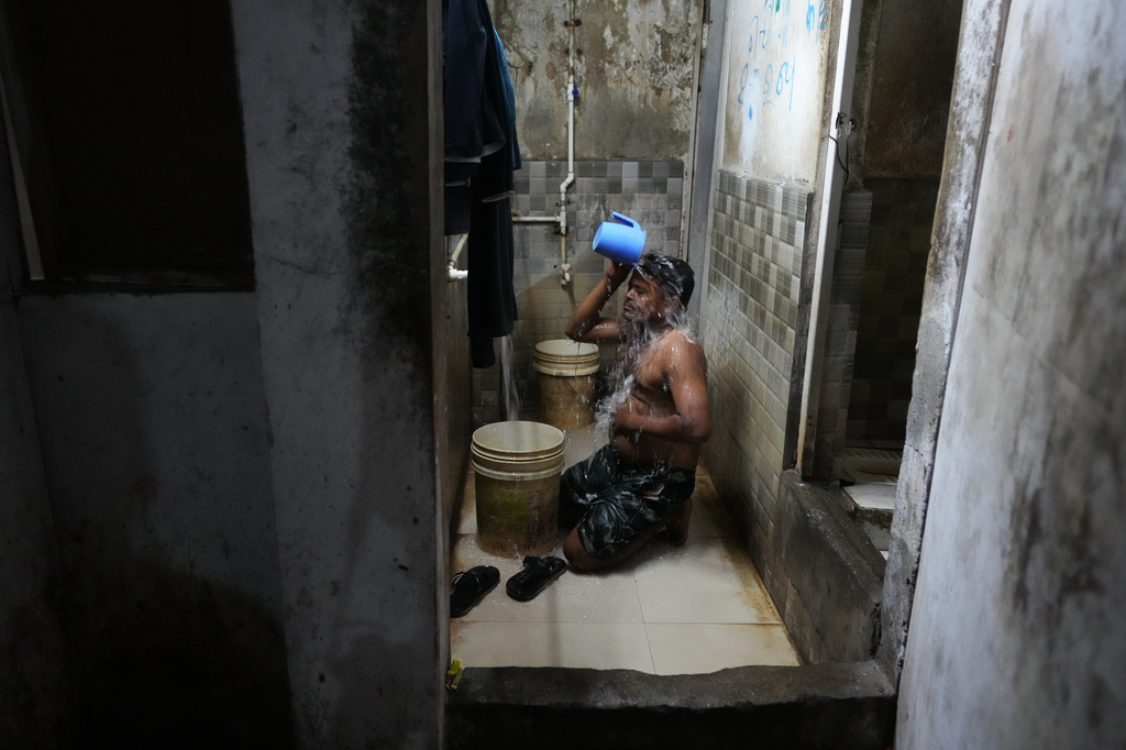 Power loom factory worker Sibaram Pradhan takes a bath after a day's work at his residential quarters in Surat, India, Wednesday, May 27, 2026. (AP Photo/Ajit Solanki)