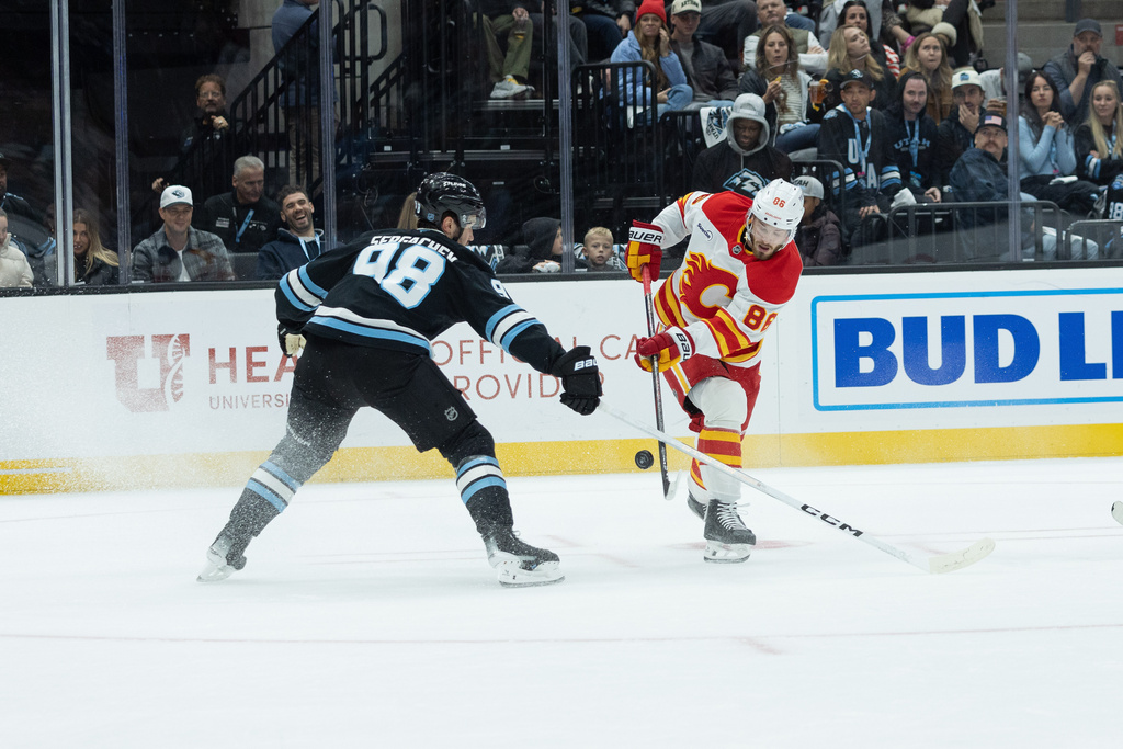 Calgary Flames left wing Joel Farabee (86) shoots the puck against Utah Mammoth defenseman Mikhail Sergachev (98) during the first half of an NHL hockey game Wednesday, October. 15, 2025, in Salt Lake City. (AP Photo/Melissa Majchrzak)