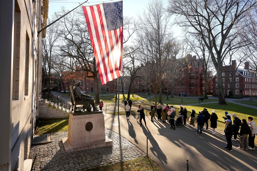 FILE - People take photos near a John Harvard statue, left, on the Harvard University campus, Jan. 2, 2024, in Cambridge, Mass. r. (AP Photo/Steven Senne, File)