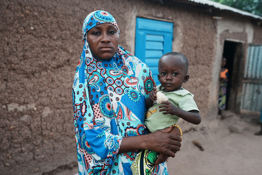 Aboudou Salamatou, carries her child Oumarou Zakari who suffers from stunted growth outside their home in N'dali, northern Benin, Sunday, May 17, 2026. (AP Photo/Sunday Alamba)