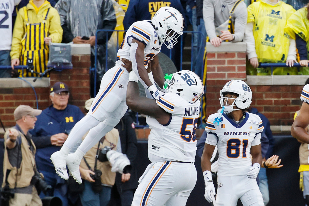 UTEP running back Lamar Sperling (32) is hoisted by offensive lineman Brian Williams Jr. (56) after catching a touchdown pass against Michigan during the first half of an NCAA college football game Saturday, Sept. 19, 2026, in Ann Arbor, Mich. (AP Photo/Duane Burleson)