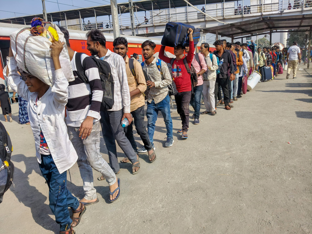 Textile workers returning to their hometowns stand in a queue to board a train following a brief shutdown of their factories caused by gas shortage and unavailability of LPG for homes, in Surat, India, Monday, March 16, 2026. (AP Photo)