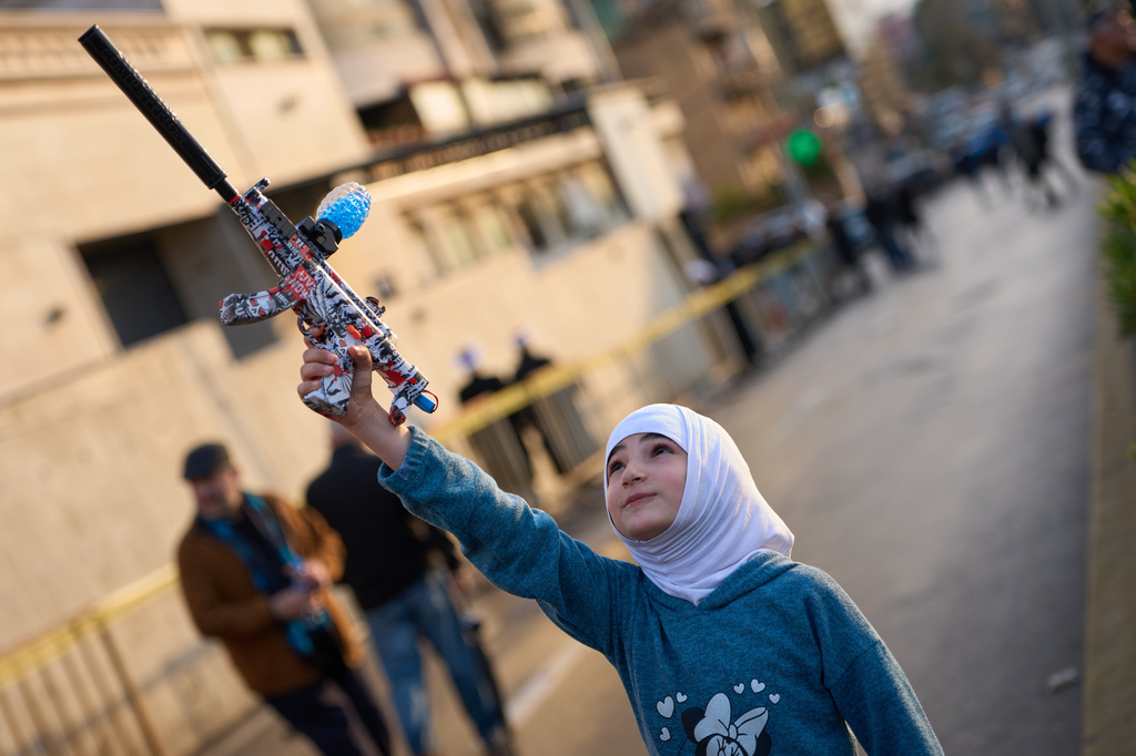 A girl holds a toy gun during a protest outside Iran's embassy, where dozens of people gathered waving Hezbollah and Iranian flags in solidarity with the Islamic Republic, in Beirut, Lebanon, Thursday, March 26, 2026. (AP Photo/Emilio Morenatti)